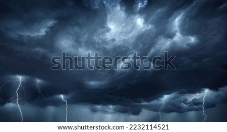 Thunderous dark sky with black clouds and flashing lightning. Panoramic view. Concept on the theme of weather, natural disasters, storms, typhoons, tornadoes, thunderstorms, lightning, lightning. Royalty-Free Stock Photo #2232114521