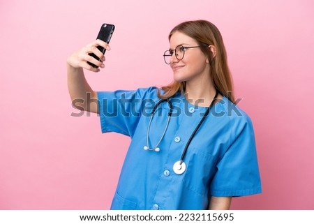 Young surgeon doctor woman isolated on pink background making a selfie