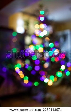 Blurred bright lights of garlands of Christmas tree in home interior. Vertical format.