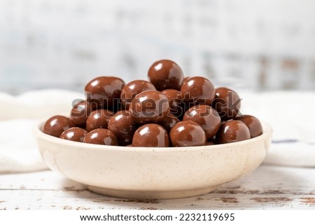 Chocolate coated hazelnut dragee. Hazelnut dragee chocolates on a white wood background. close up
