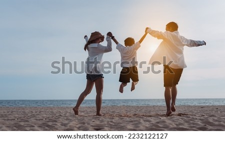 Happy asian family jumping together on the beach in holiday vacation. Silhouette of the family holding hands enjoying the sunset on the sea beach. Happy family travel, trip  family holidays weekend.