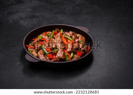 Delicious Asian teriyaki meat with red and green bell peppers and sesame seeds close-up on a plate on the table