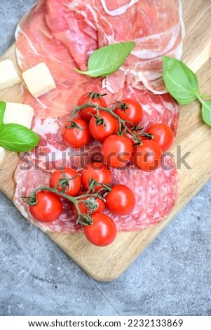 Slices Of  Traditional Italian antipasti mortadella Bolognese,salame Milano, parmesan cheese  and prosciutto crudo   on a wooden  cutting board.