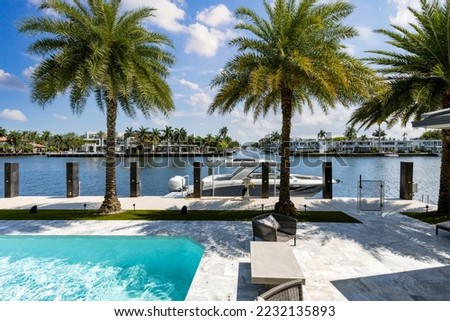 Backyard of modern luxury house facing the barcelona canal river, in fort lauderdale, miami, swimming pool with sun loungers, outdoor armchairs, tile floor Royalty-Free Stock Photo #2232135893