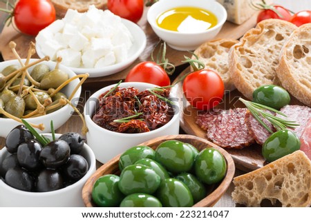 assorted Italian antipasti - olives, salami, pickles and bread, close-up
