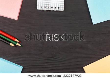 RISK - text, stickers and colored pencils on a black wooden table. Business concept: buying, selling, commerce (copy space).