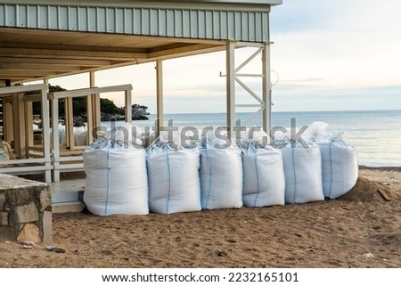 There are many large white sandbags on the beach for flood protection. Sandbags to protect buildings and coastal structures to protect against tsunamis and floods. water protection structures. Royalty-Free Stock Photo #2232165101