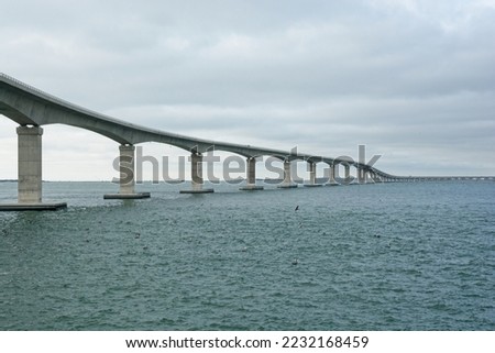 Pelicans and seabirds dot the waters around concrete box girder bridge spanning Oregon Inlet. The Marc Basnight bridge between Bodie Island and Pea Island on the Outer banks of North Carolina Royalty-Free Stock Photo #2232168459