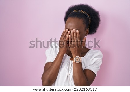 African woman with curly hair standing over pink background rubbing eyes for fatigue and headache, sleepy and tired expression. vision problem 