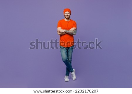 Full body young smiling european man 20s he wear red hat t-shirt hold hands crossed folded look camera isolated on plain pastel light purple background studio portrait. Tattoo translates life is fight