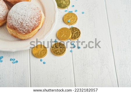 Happy Hanukkah. Hanukkah sweet doughnuts, gift boxes, white candles and chocolate coins on white wooden background. Image and concept of jewish holiday Hanukkah. Top view.