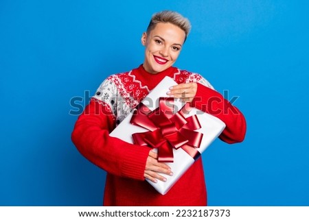 Closeup portrait photo of young short blonde hair hug her new surprise box from saint nicholas wear warm sweater isolated on blue color background