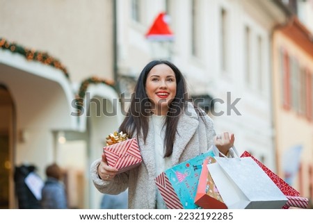 Christmas shopping. Young beautiful dark haired woman buys gifts for the New Year holidays. Winter holiday. Happy.