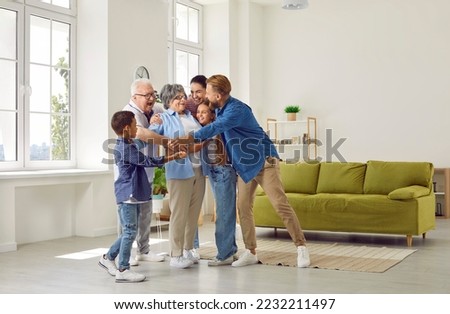 Happy large cute family hugging their beloved grandmother in a cozy bright spacious room at home. Concept of a dynasty in three generations, family ties, unconditional love, family relations, reunion. Royalty-Free Stock Photo #2232211497