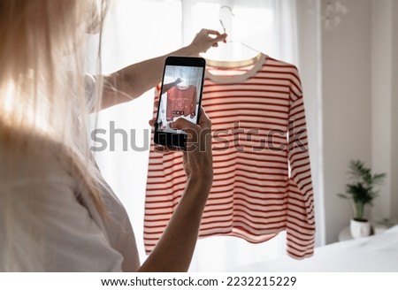 Woman taking photo of striped t-shirt on smartphone 
