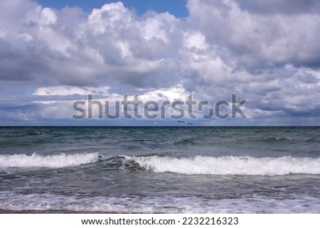 Seascape with storm sea waves with foam under heavy cumulonimbus on the sky to horizon