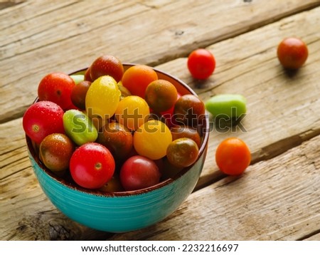 Appetizing colorful tomatoes in a blue bowl on a wooden kitchen table. Useful vegetable crop, organic food, healthy lifestyle. Food background. Advertising, banner.