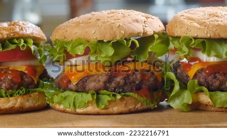 Big appetizing burgers with fresh tomatoes, onions, juicy grilled beef patty and cheese. Fast food, Close-up