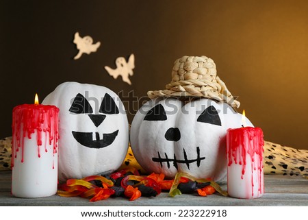 White Halloween pumpkins and candles on wooden table on dark color background