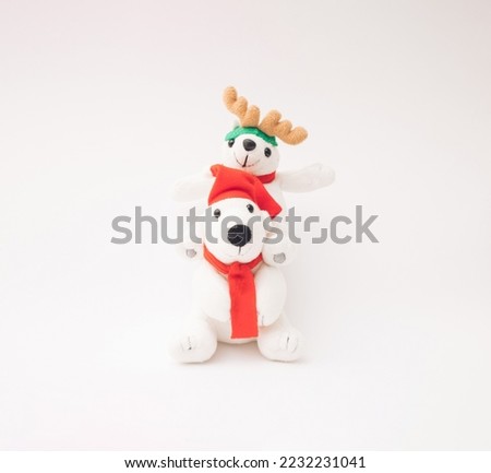 Two happy plush toy polar bears with Santa Claus hat, scarf and reindeer antlers.