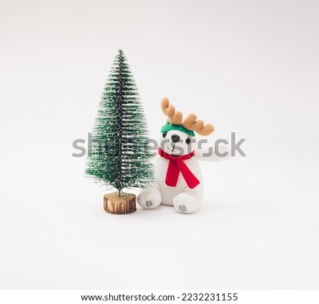 New Year Christmas tree with plush polar bear and reindeer antlers on a white background.