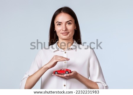 beautiful woman in white shirt holding little red car Royalty-Free Stock Photo #2232231983