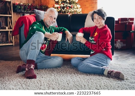 Full size portrait of two peaceful lovely people sitting carpet floor hold tea mug enjoy newyear magic indoors