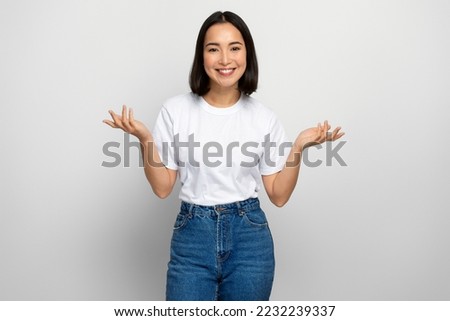 Uncertain positive woman with raised arms, dont know what to do. Indoor studio shot isolated on white background Royalty-Free Stock Photo #2232239337
