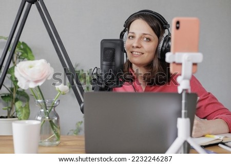 female musician and podcaster creates audio and video content for social media. a confident European woman speaks into a microphone and records a lesson or interview. streaming and working online on