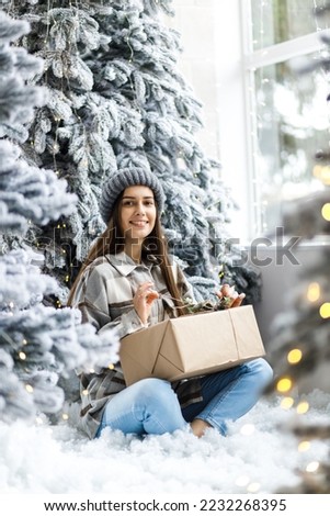 Beautiful girl at a New Year's photo shoot in the studio. New year concept. Long hair and makeup. The girl opens a gift.