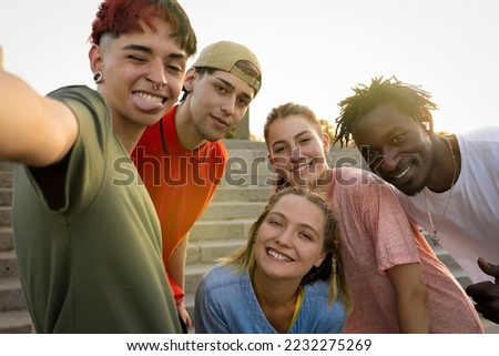 Happy friends of different cultures and races taking a selfie in the sunset light. Concept of youth and friendship with young people having fun together. Selective focus