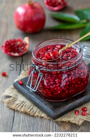 Homemade Pomegranate Tea made from juice and pomegranate seeds in a glass jar. Wooden table, selective focus, vertical.
