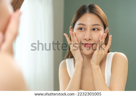 Freshness, nice healthy. Beautiful asian young woman, girl looking on reflection in mirror, hand touching face with makeup cosmetic, skin care routine at home. Happy smile female with natural beauty. Royalty-Free Stock Photo #2232301005