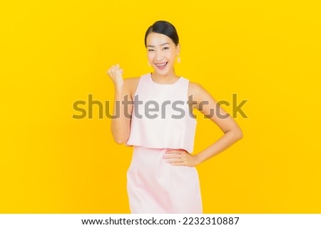 Portrait beautiful young asian woman smile with action on yellow color background