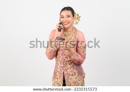 Young beautiful woman dress up in local culture in southern region posing with smartphone  and credit card in hand on white background