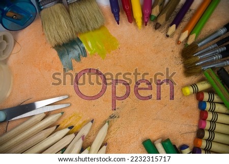 Overhead shot of school supplies with Open text. Brushes, pencils, artistic tools. Art And Craft Work Tools.