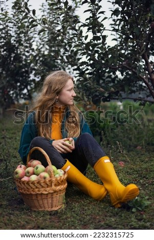 apple harvest and rural aesthetic. beautiful girl with a basket of apples in the background of the garden
