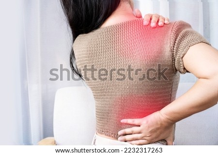 woman suffering from shoulder pain or upper back spreading to the lower back Royalty-Free Stock Photo #2232317263