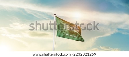 Saudi Arabia national flag waving in beautiful sky. Royalty-Free Stock Photo #2232321259