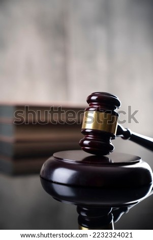 Mallet of the judge and scales of justice. Glossy table and grey stone background. Law concept.