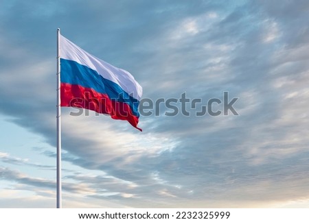 Waving Russian flag against a blue sky with clouds and empty space for text. Room for text. National flag of the Russian Federation. Royalty-Free Stock Photo #2232325999