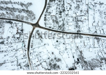 aerial drone photo looking down onto the rooftops of snow-covered suburban district