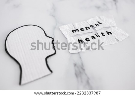mental health and reaching out for help conceptual image, cardboard head next to scrunched up torn paper with text