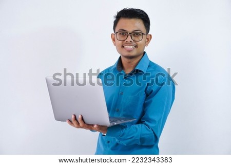smiling or happy asian businessman with glasses holding laptop wearing blue shirt isolated on white background