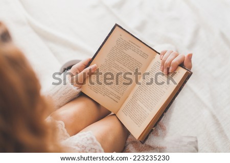 Soft photo of woman on the bed with old book and cup of coffee, top view point Royalty-Free Stock Photo #223235230
