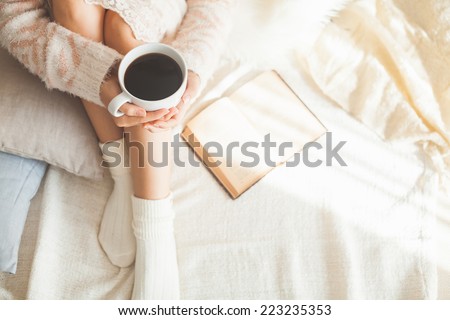 Soft photo of woman on the bed with old book and cup of coffee in hands, top view point Royalty-Free Stock Photo #223235353