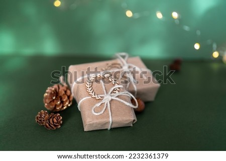 Christmas and zero waste, eco friendly packaging. wrapped gifts in craft paper with pine cones and nut on a green background. ecological Christmas holiday concept, eco decor