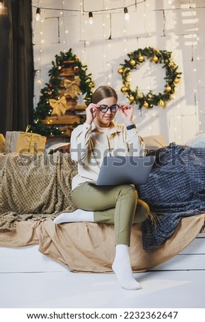 Beautiful Merry Christmas woman drink a sweet cup of hot cocoa, wear comfortable home clothes, look at the laptop, work remotely for the new year, plaid, New Year's winter mood.