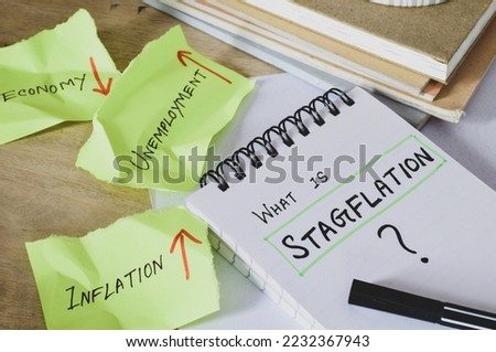 What is Stagflation question in notepad with it's components on torn papers on desk. Selective focus.