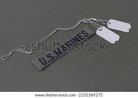 U.S. MARINES Branch Tape with dog tags on olive drab uniform background